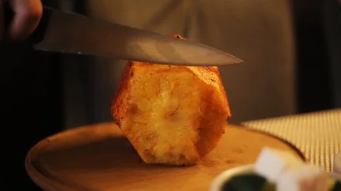 Person cutting fried pineapple in kitchen of restaurant. Another person holding Stock Footage 98560567