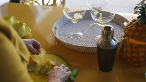 A person is cutting up a lime on a table with a tray of drinks and a pineapple Stock Footage 297870628