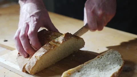 A person is cutting a loaf of bread with a knife Stock Footage 305647444