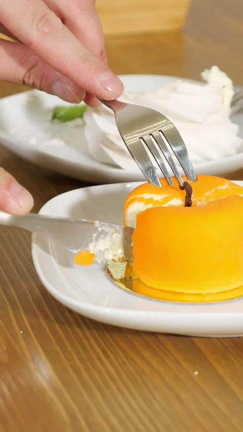 Person cutting orange mousse cake dessert with knife and fork Vídeos de archivo 341192791