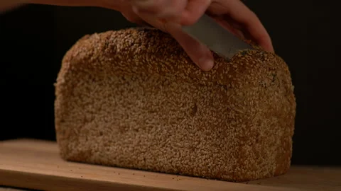 Person Cutting A Piece Of Whole Wheat Bread with Sesame Seeds Stock Footage 130444953