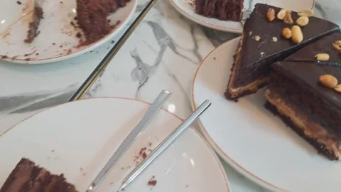 A person cutting a slice of chocolate cake on a marble table with a knife and Stock Footage 343614952