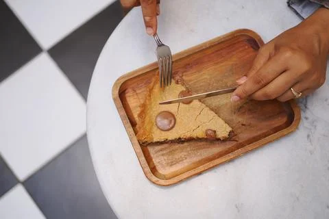 Person cutting a slice of a cookie pie on a wooden tray Stock Photos