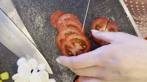 A person is cutting a tomato into slices Stock Footage 280002425