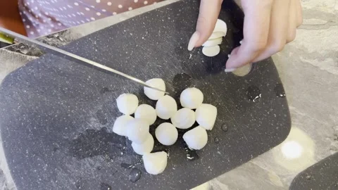 A person is cutting up a tray of small white balls on a cutting board 库存影片 282298097