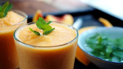 Person decorates orange smoothie 動画素材 79932336