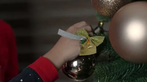 A person is decorating a Christmas tree with a golden ornament Stock Footage 319829455