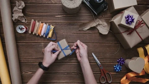 Person decorating wrapped present with blue ribbon Stock Footage 69928712