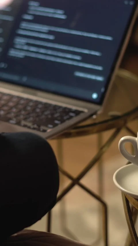A person is deeply focused on coding on their laptop, with a warm cup of coffee Stock Footage 293208959