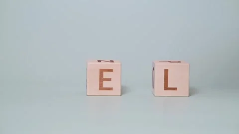 A person demonstrates how to form words using wooden blocks on a plain Stock-Footage 338187588