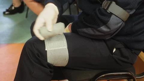 Person is demonstrating a first aid procedure by applying a bandage to leg. The Video stock 282239236