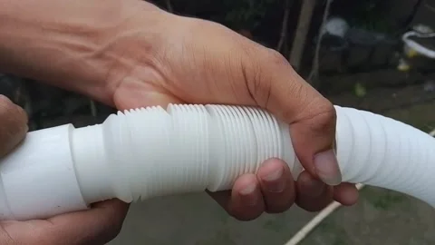 Person demonstrating flexible white plastic hose extending and contracting. 스톡 동영상 346617813
