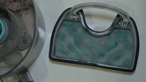 A person is demonstrating how to clean a vacuum cleaner filter at home. Stock Footage 339005222