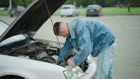 Person in denim working on automobile with dedication outside, Man in denim Stock Footage 329440134