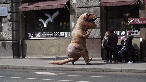 Person in dinosaur costume prankster running in front of cafe Stock Footage 84928853