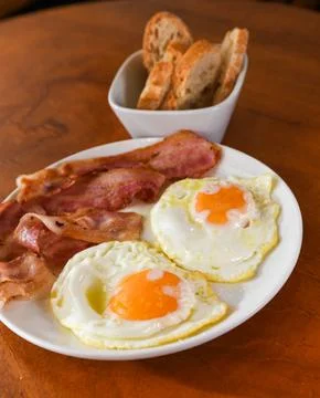 Person Dipping Bread into Fried Egg Yolk for Breakfast Stock Photos