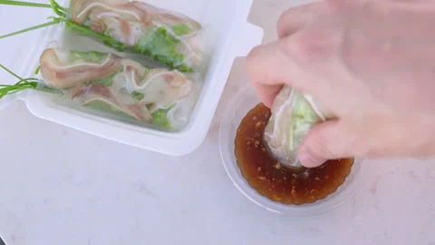 Person dipping vietnamese spring roll with pork ear into sauce Stock Footage 337360384