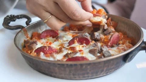 Person dips bread into hot skillet with melted cheese and meat. Video stock 332896758