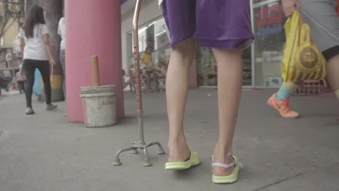 Person with disability walking on busy side walk Stock Footage 230088037