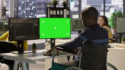 Person with disability in wheelchair checking code on mockup PC 写真素材