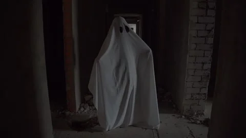 Person disguised as ghost wobbles gently in dim light, oversized black eyes and Stock Footage 320246393