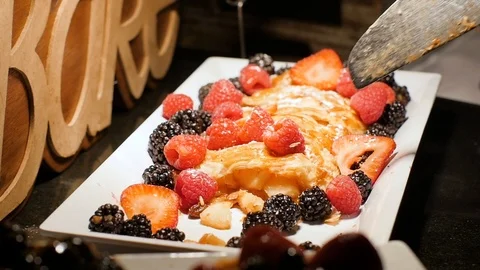 A person dishes up a slice of apple pastry dessert with raspberries Stock Footage 86440341