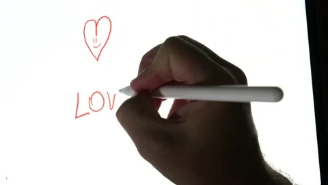 Person drawing in a tablet a red hurt and writing love and then cross out Stock-Footage 169322480