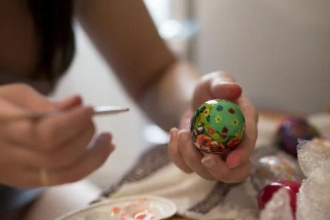 A person draws a brush on an Easter egg with different colors Stock Photos
