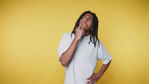 Person with dreadlocks thinking in front of a yellow background while touch.. Stock Footage 328248791