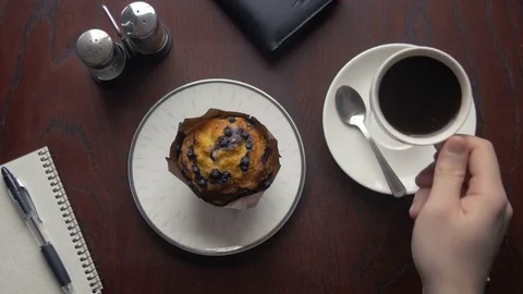 Person drinking a coffee and tasting a delicious cupcake Stock Footage 75456579