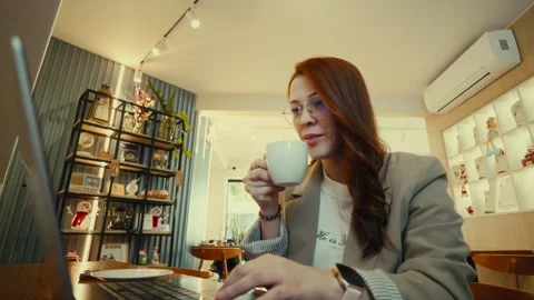 Person drinking coffee while working on laptop indoors Stock Footage 323928232