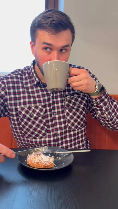 Person drinking from mug at table with pastry, cozy lifestyle moment in casual h Stock Footage 334790686