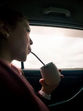 Person drinks from a container using a straw in a vehicle Photos