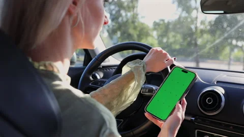 Person Driving a Car While Holding Smartphone with Green Screen: Exploring Stock Footage 314460209