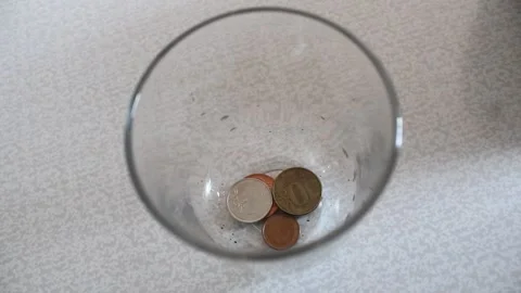 Person Dropping Coins into a Glass Container for Savings Stock Footage 345639977