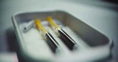 Person dropping an empty used syringe into a tray Stock Footage 255750947