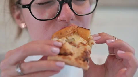 A person is eating a slice of pizza, showcasing enjoyment and interaction Stock Footage 337556811