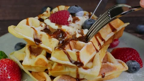 Person eating soft waffles using a fork, cutting a piece of fluffy waffle with Stock Footage 234083049