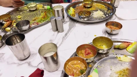Person eating traditional Indian food with various dishes on a metal plate .. Stock Footage 263157568