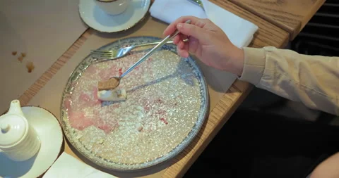 Person eats dessert with long silver spoon at restaurant Stockbeeldmateriaal 136651534