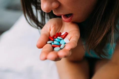 Person eats a handful of tablets and pills from the hand Stock Photos
