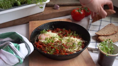 Person eats Izrael scrambled eggs shakshuka with whole grain dark bread Stock Footage 131857005
