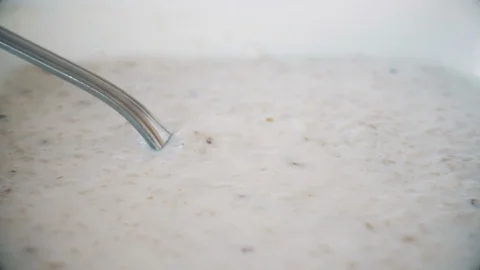 Person eats oatmeal with milk a spoon. Slow motion static close up shot filmed Stock Footage 107740740