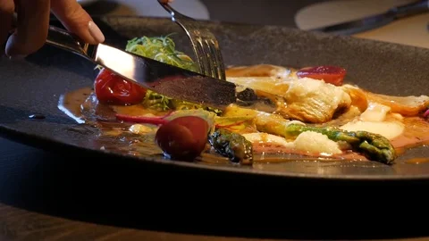 A person eats from a plate with a fork and a knife Stock Footage 87311855
