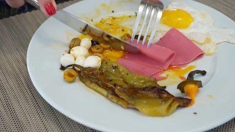 A person eats scrambled eggs with grilled vegetables and sausage. Breakfast.  Stock Footage 125553218