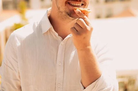 Person eats snack outdoors while enjoying sunny weather in casual setting wit 스톡 사진