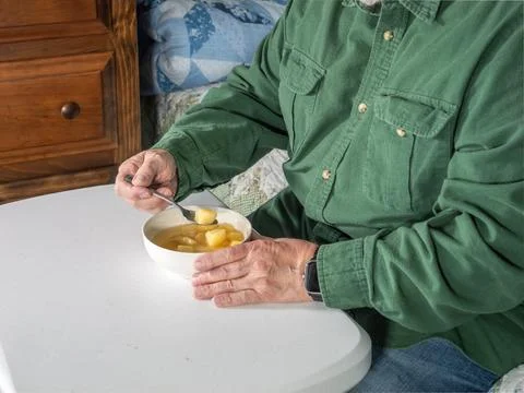 Person Eats Soup While Sitting at a Table in a Cozy Indoor Setting in the A.. Foto stock