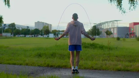 A person energetically jumping rope in the park during sunrise hours Stock Footage 317514161