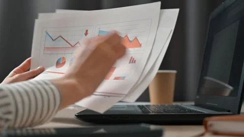 A person is engaged in reviewing and sorting through documents featuring charts Stock Footage 339005538