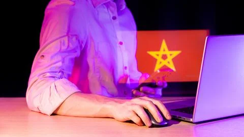 Person engaging with tech devices amid projected red banner with star motif Foto stock
